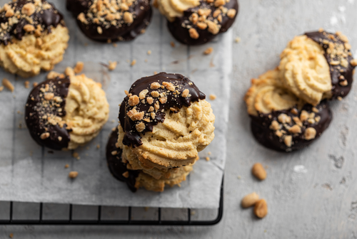 Sablés viennois maison en forme de W, trempés dans du chocolat noir, disposés sur une plaque.