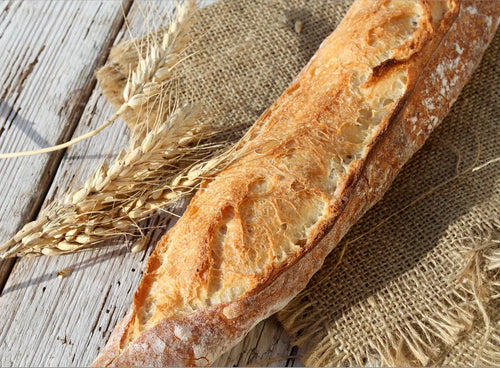 Baguettes françaises dorées et croustillantes, posées sur une grille de refroidissement après cuisson.