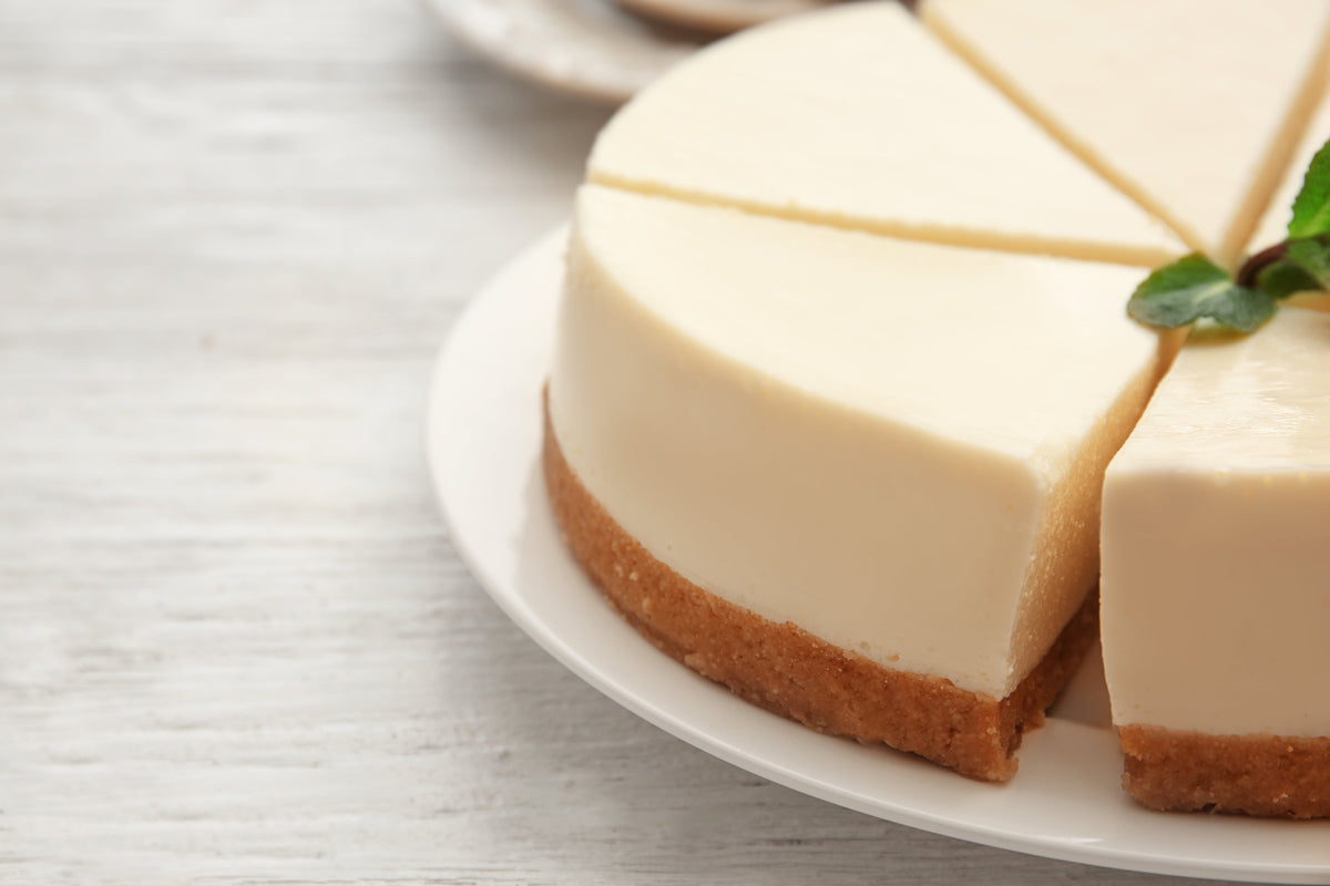 Cheesecake crémeux à l'ananas sur une table en bois avec des tranches d'ananas fraîches à côté et une cuillère en argent.
