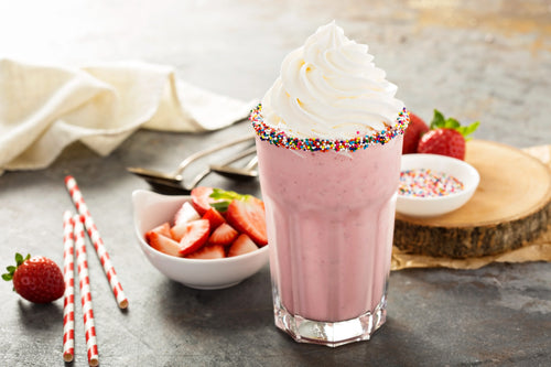 Milkshake à la fraise frais et onctueux servi dans un grand verre avec une paille.