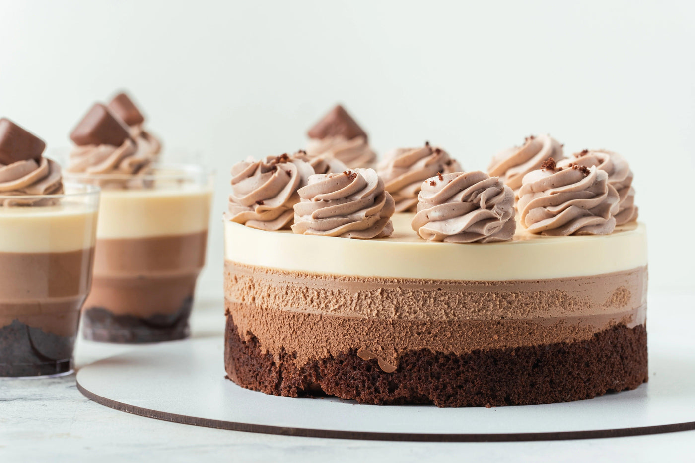 Un gâteau en trois couches de mousses au chocolat noir, au lait et blanc, surmonté de copeaux de chocolat et chantilly chocolat