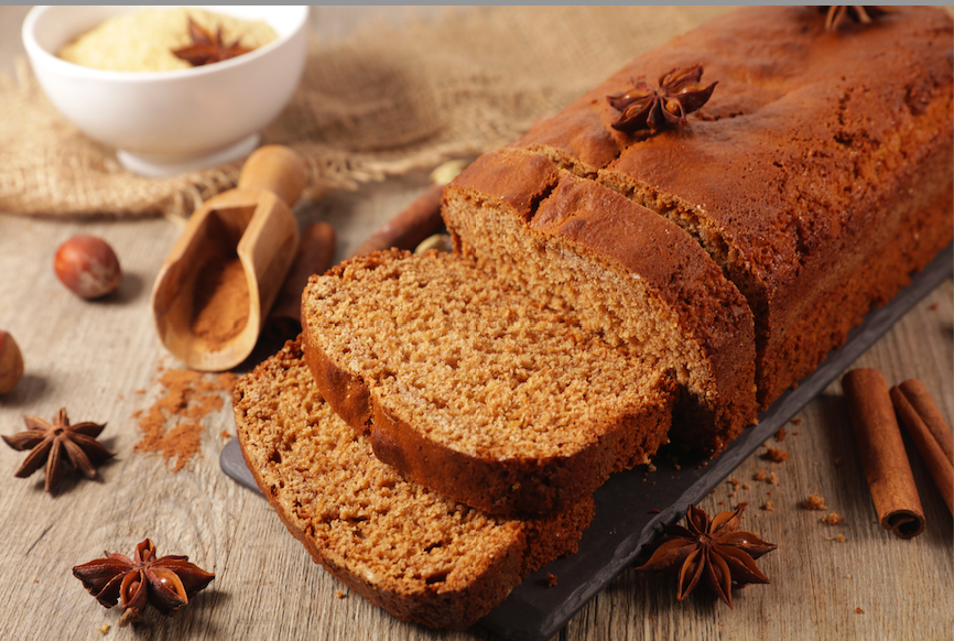 Pain d’épices maison moelleux au miel et aux épices, découpé en tranches sur une planche en bois.