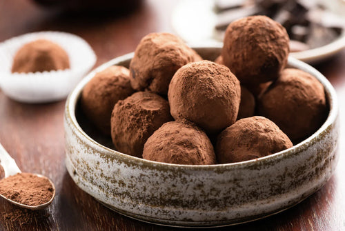Truffes au chocolat maison roulées dans du cacao, noix de coco et éclats de noisettes, présentées en caissettes festives.