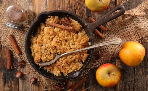 Crumble aux pommes et noisettes doré au four, servi dans un plat en céramique avec une boule de glace vanille