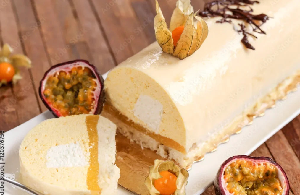 Bûche glacée exotique mangue et passion, nappée d’un glaçage miroir brillant, décorée de physalis et servie avec fruits de la passion frais.