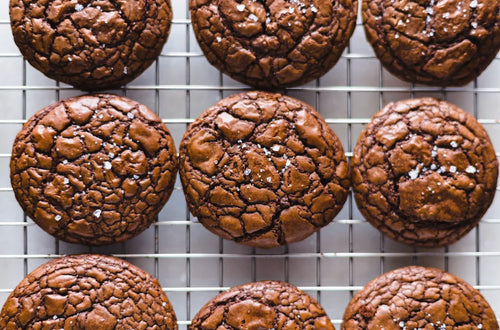 Outrageous cookies maison, au chocolat noir fondant et au cœur moelleux, disposés sur une plaque de cuisson.