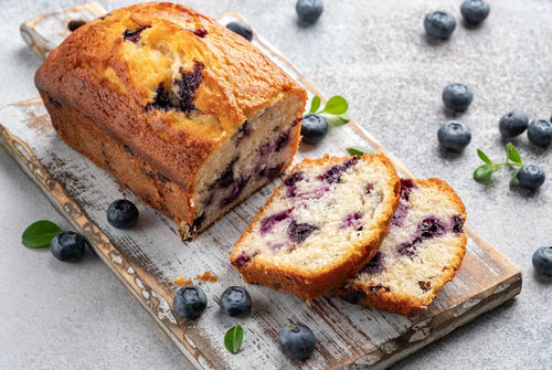 Cake doré aux myrtilles, coupé en tranches, montrant une mie moelleuse parsemée de fruits.