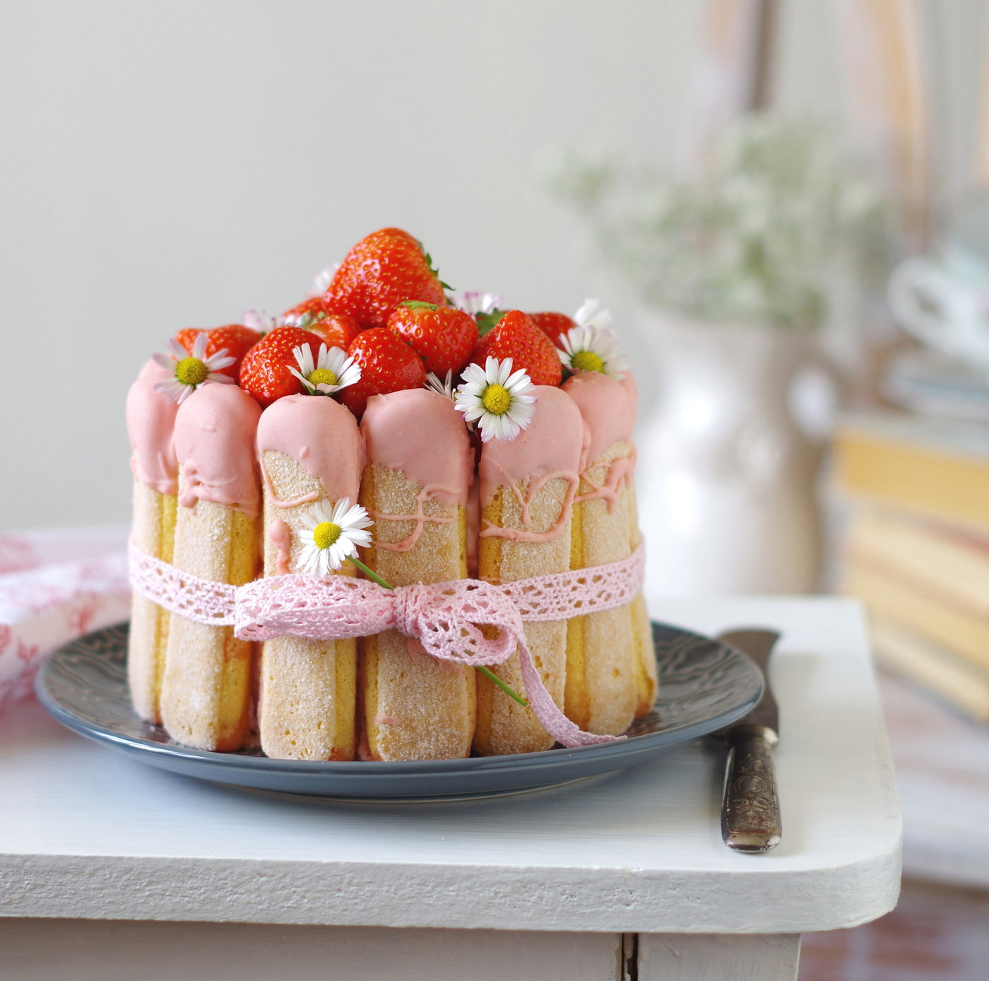 Magnifique Charlotte aux fraise sur une assiette avec des marguerites