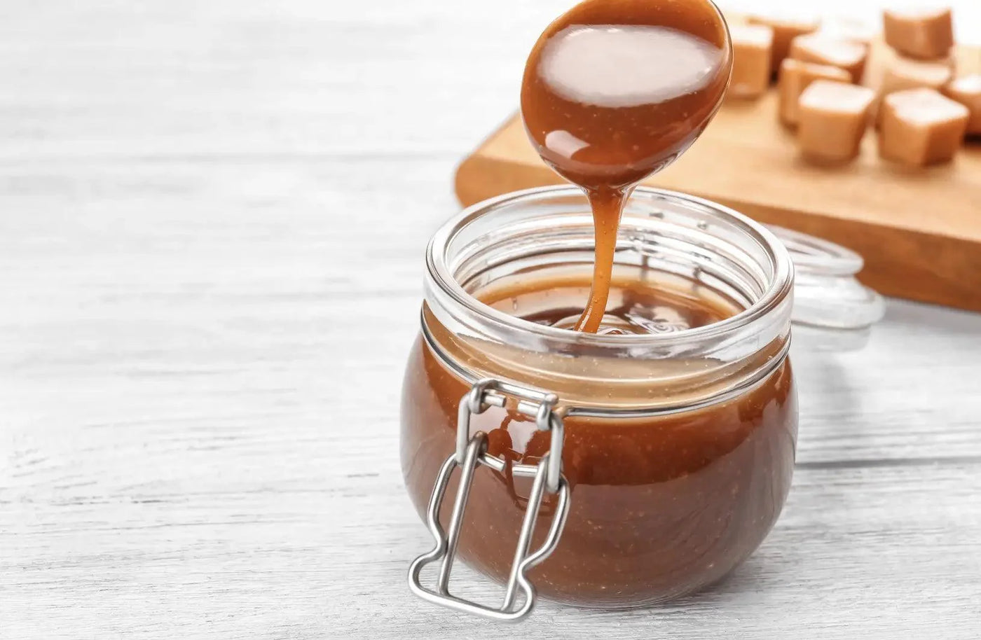 Image d'un coulis de caramel doré versé sur une cuillère, avec une texture lisse et brillante, présenté dans une cuisine lumineuse.