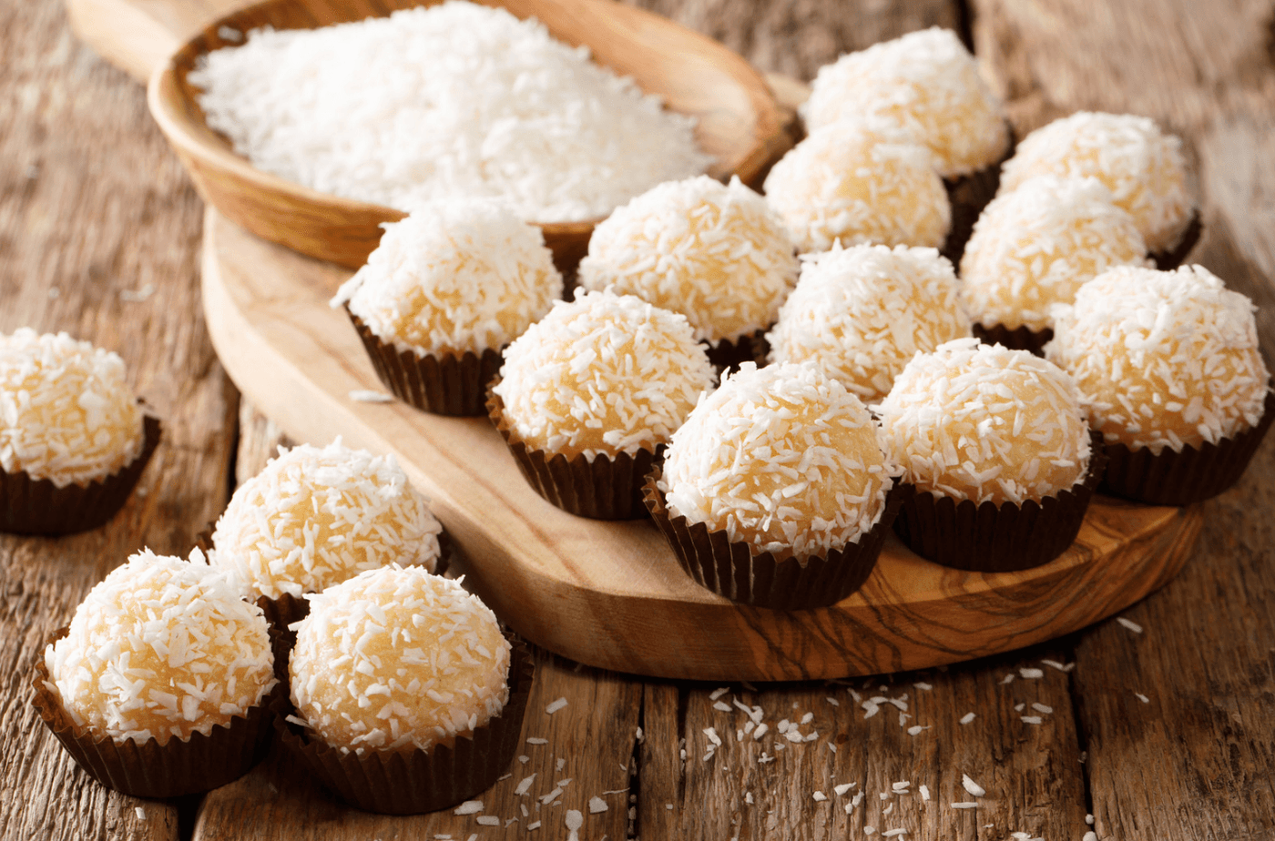 Boules de coco dorées garnies de confiture sur un plateau.