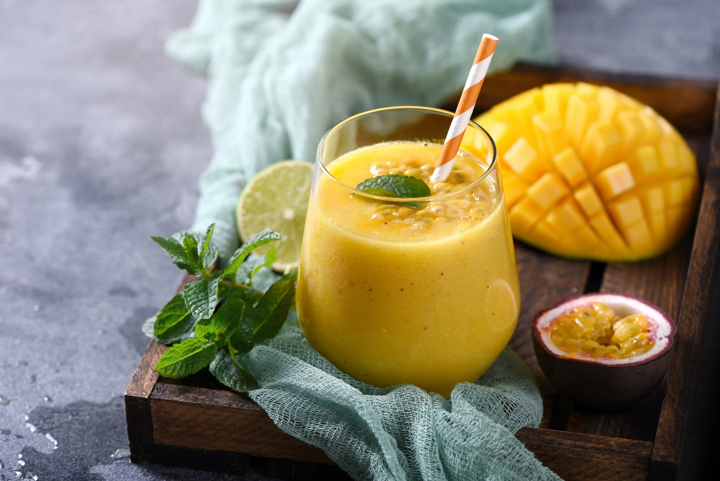 Cocktail sans alcool Joséphine Baker dans un grand verre : mélange onctueux de couleur jaune-orangé à base de mangue, fruit de la passion et lait de coco, garni d'une tranche de mangue fraîche