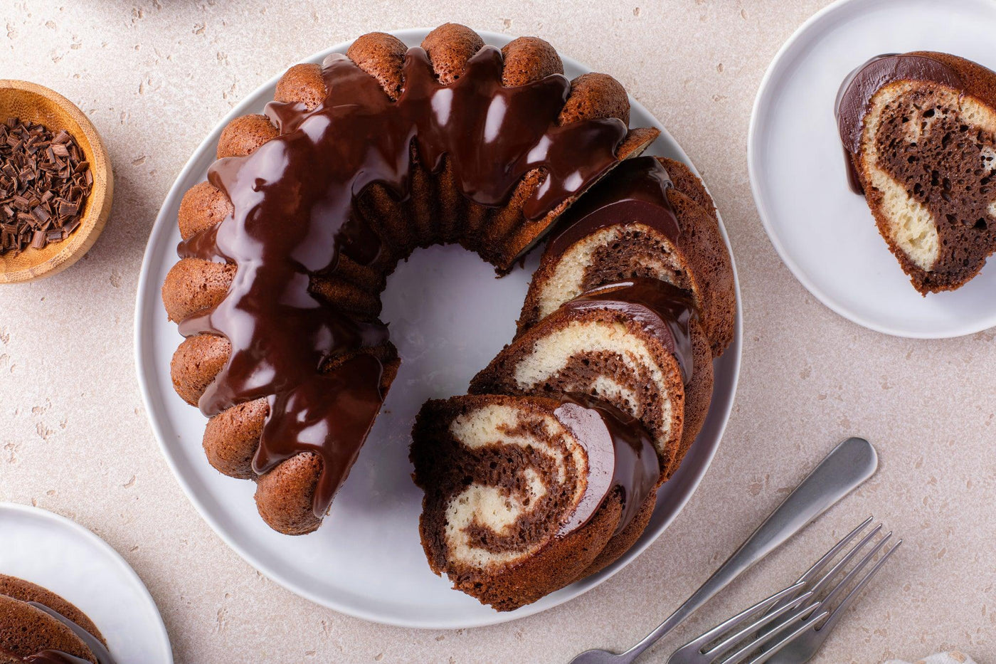 Gâteau marbré en couronne nappé de chocolat, servie avec couverts.